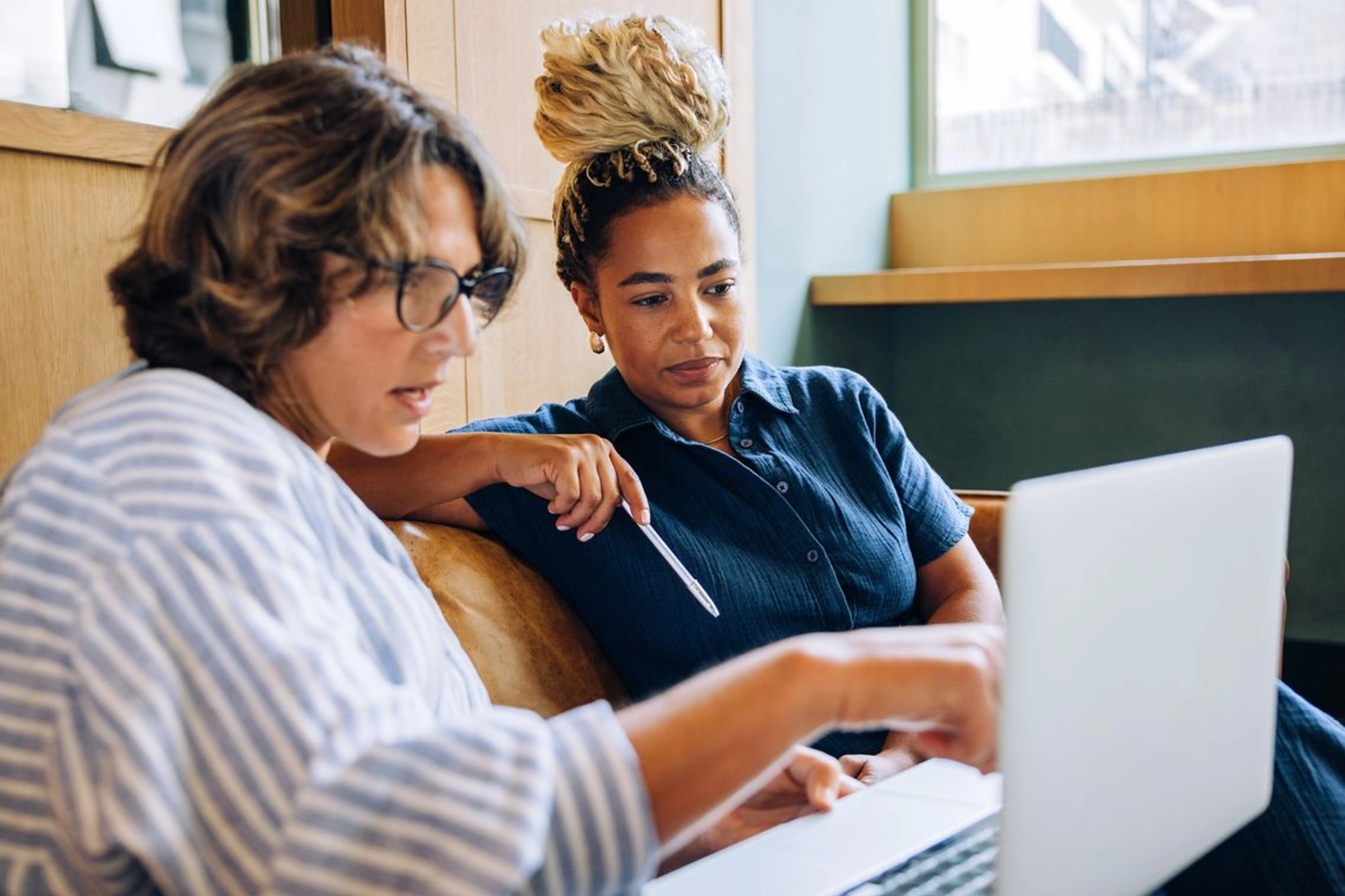 Two individuals reviewing employer-sponsored healthcare coverage details together on a laptop