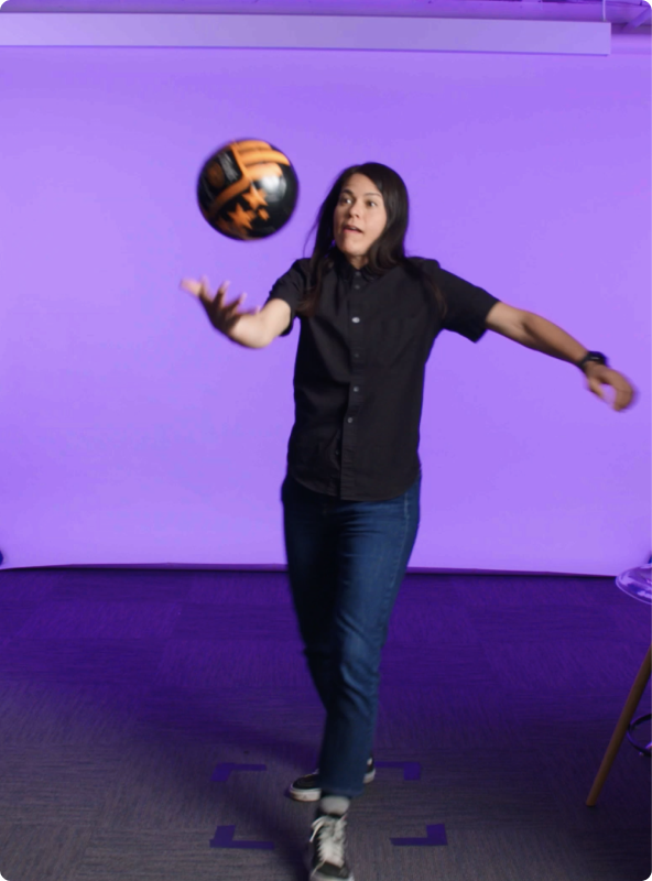 Woman wearing black shirt and jeans throwing a soccer ball in the air