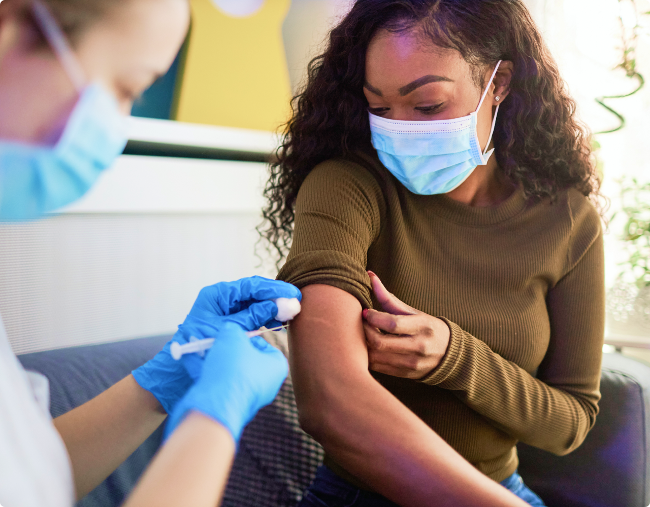 Woman with mask getting vaccination from medical professional