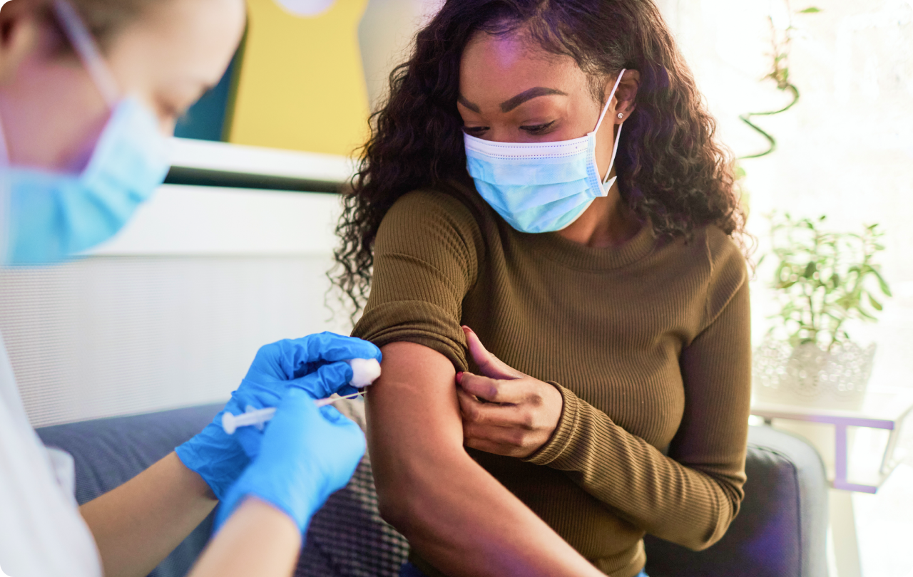 Woman with mask getting vaccination from medical professional