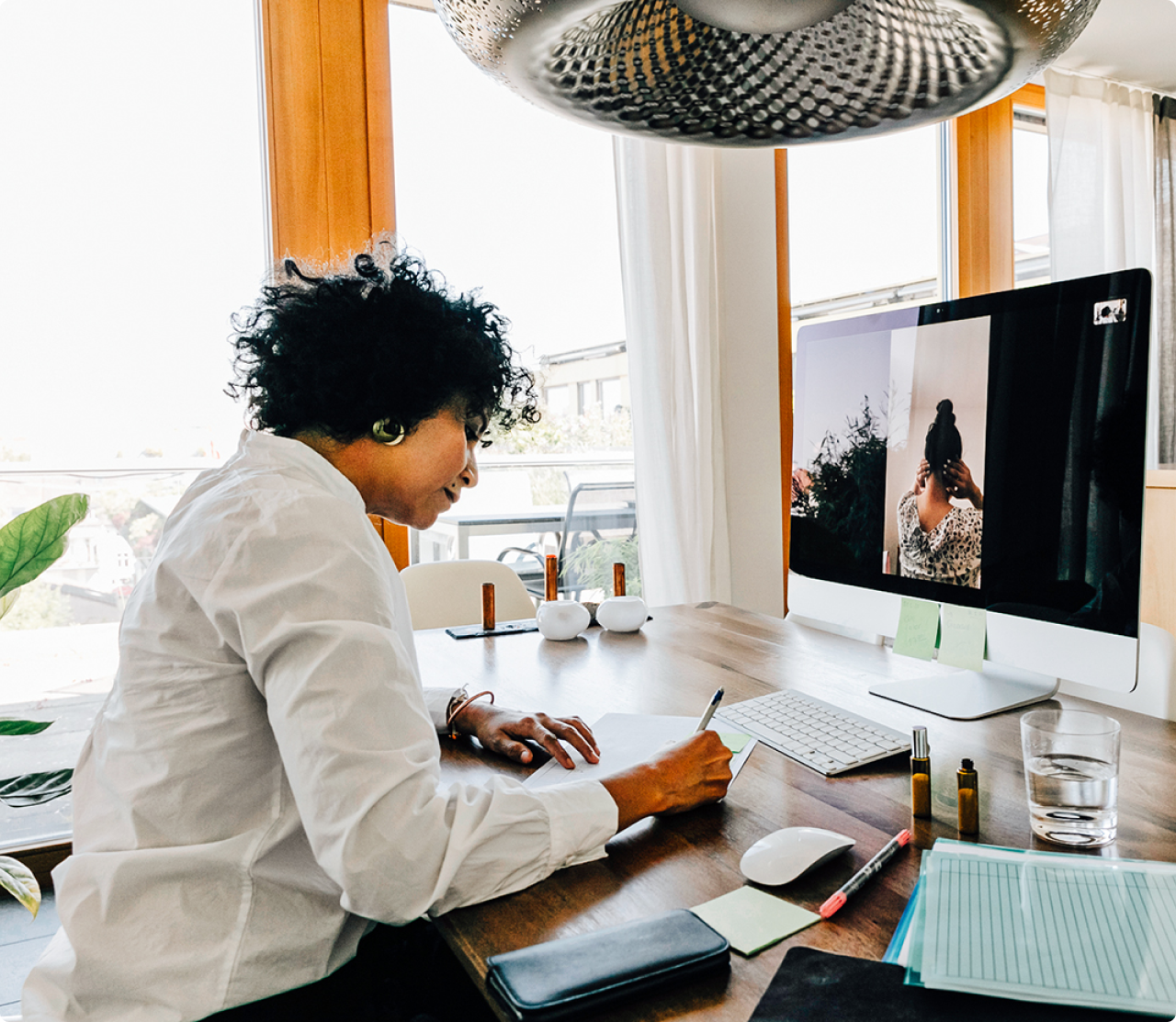 Woman sitting at desk writing in front of a computer