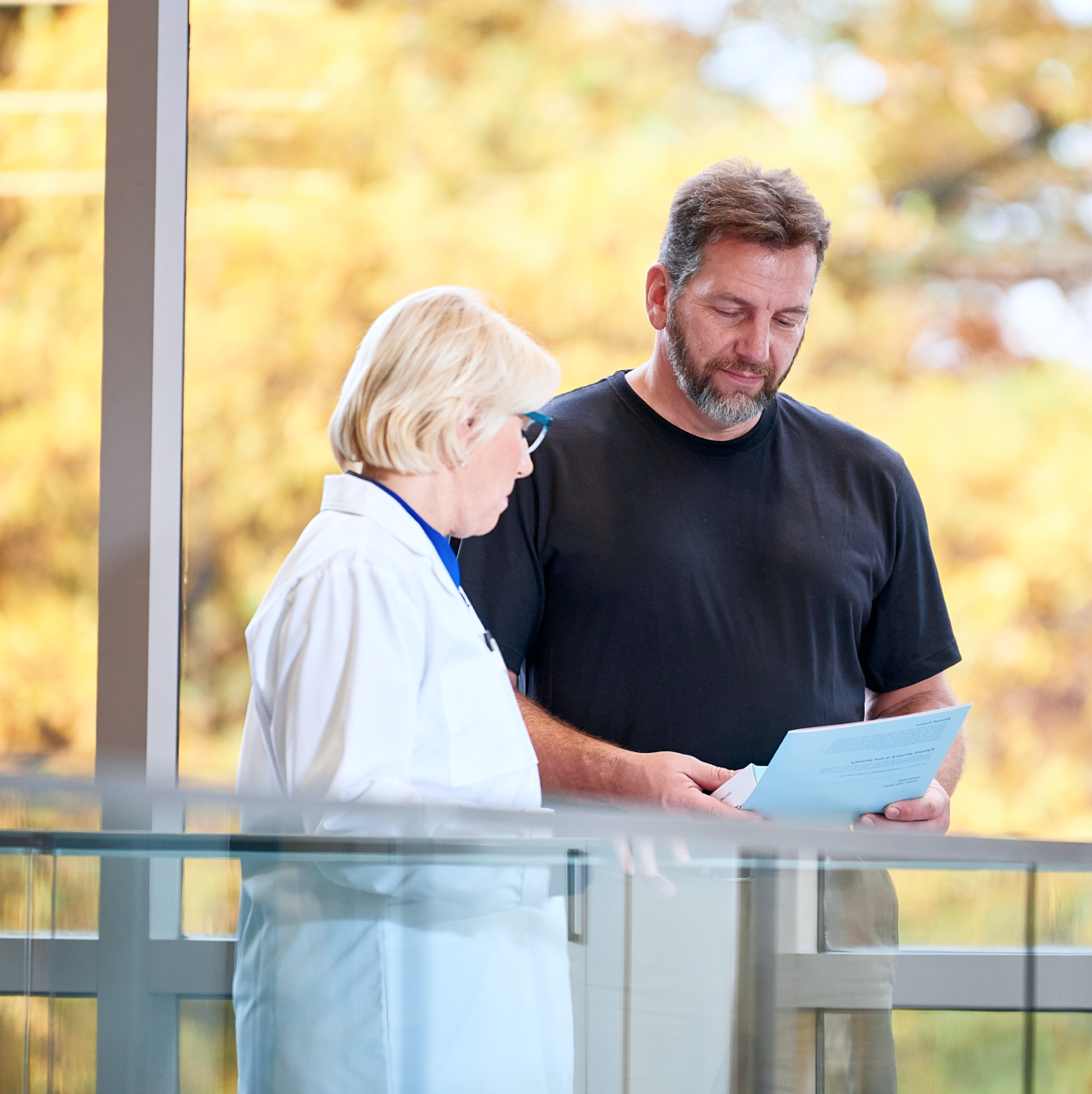 Man holding papers standing next to a woman wearing a lab coat