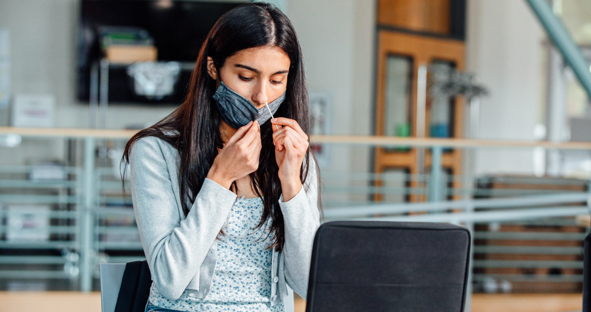 Young college student lowering mask and using Color test nose swab.