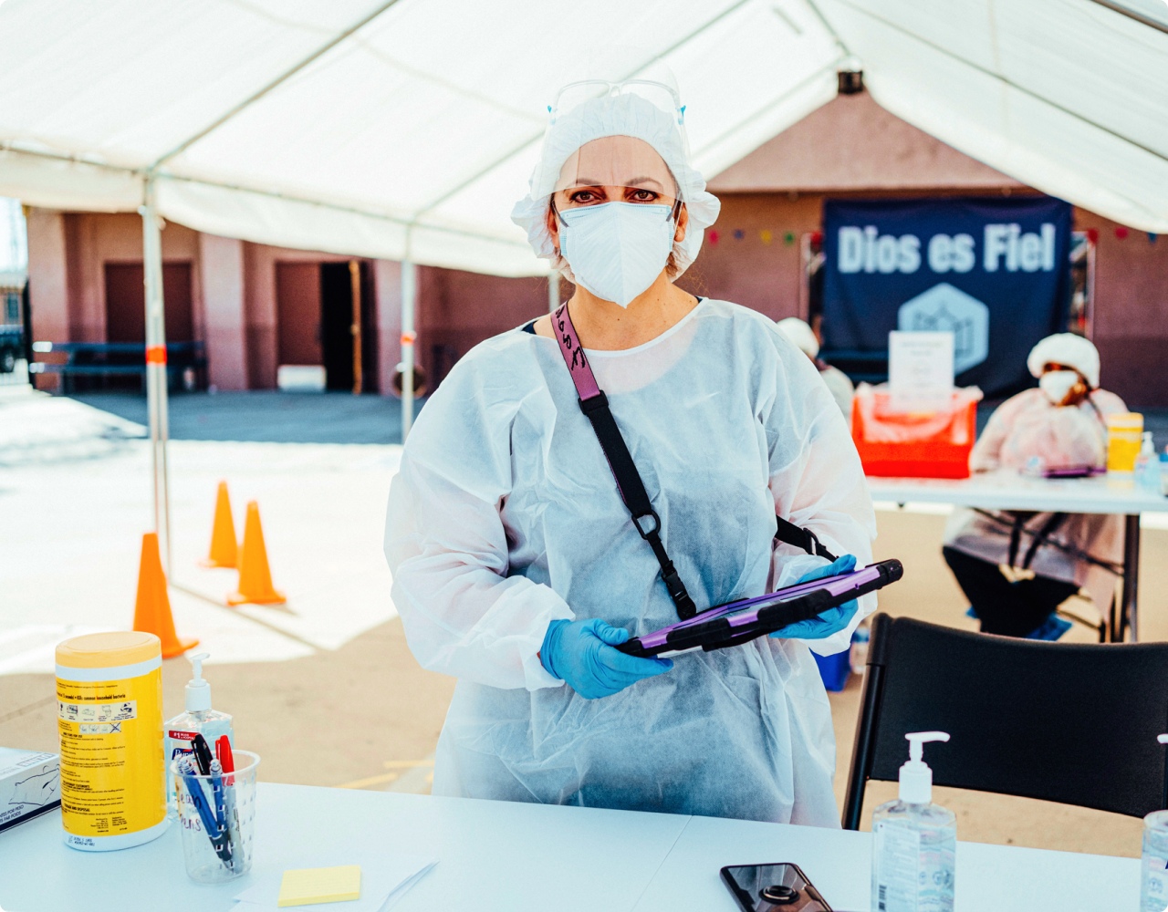 Female medical professional wearing a mask holding a tablet at a testing site