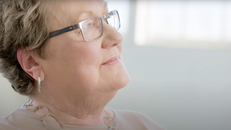 Profile close up view of a woman wearing glasses and hoop earrings