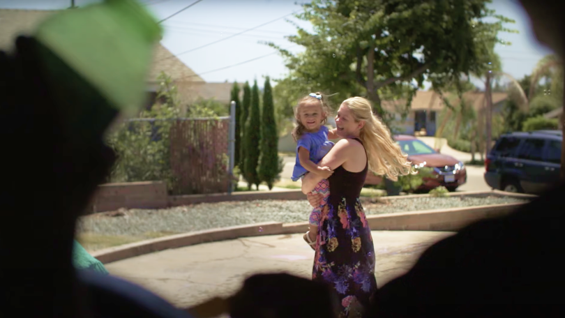 Woman outside wearing a dress holding a smiling little girl