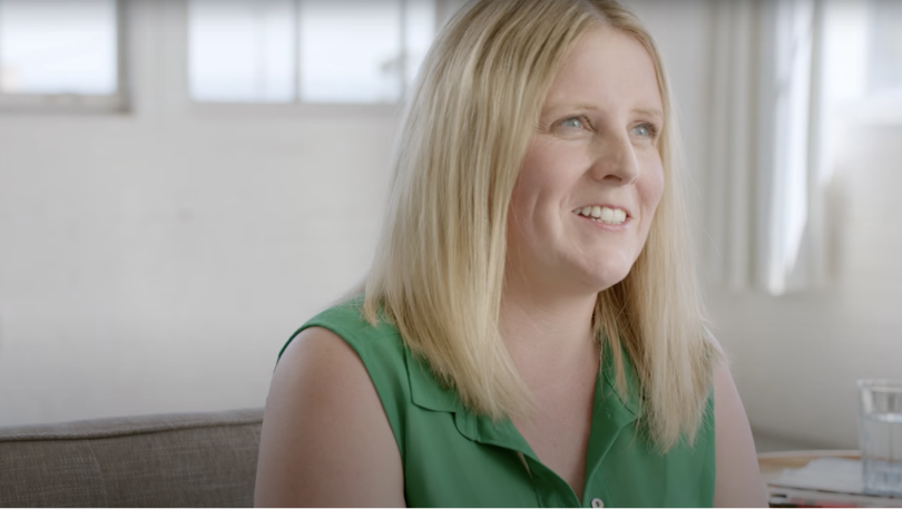 Woman sitting in a chair wearing a green shirt and smiling