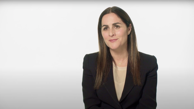 Woman wearing a black blazer looking to the side of the camera