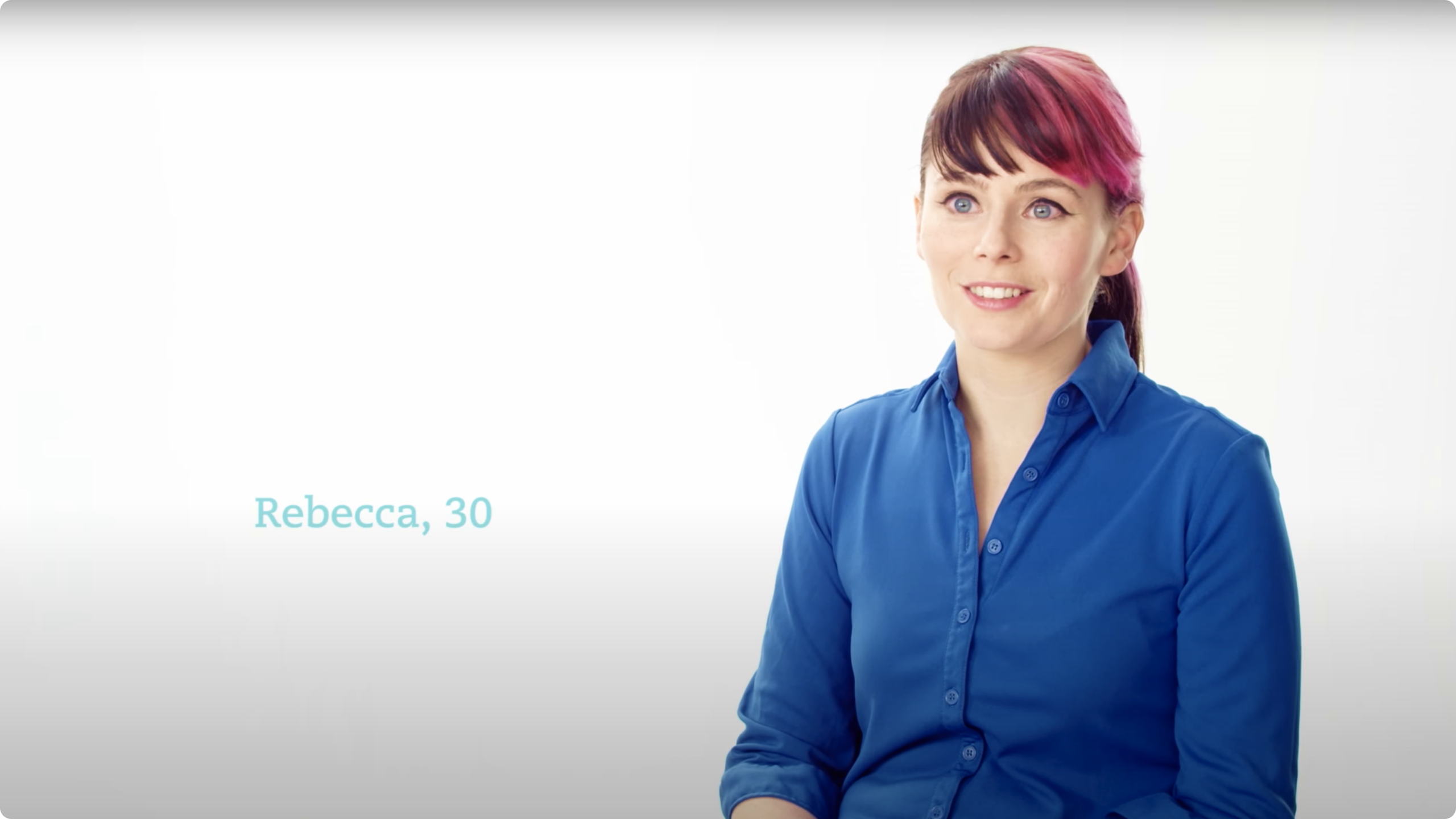 Smiling woman wearing blue collared shirt with pink and brown hair